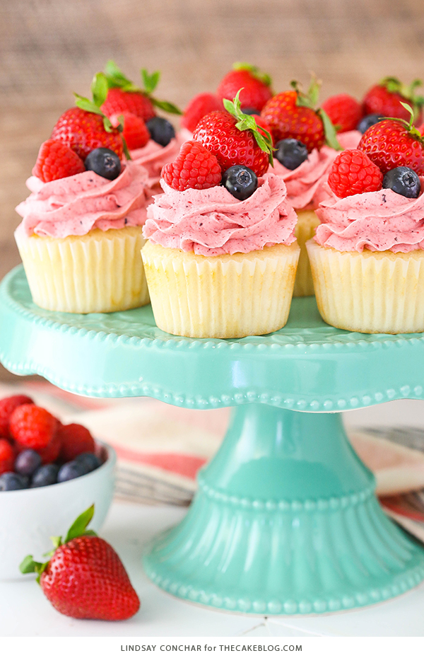 Berries and Cream Cupcakes - mixed berry buttercream paired with a moist vanilla cupcake stuffed with whipped cream cheese filling, topped with fresh strawberries, raspberries and blueberries | by Lindsay Conchar for TheCakeBlog.com