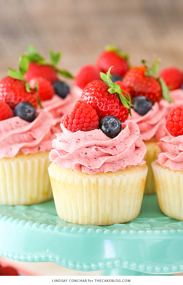 Berries and Cream Cupcakes - mixed berry buttercream paired with a moist vanilla cupcake stuffed with whipped cream cheese filling, topped with fresh strawberries, raspberries and blueberries | by Lindsay Conchar for TheCakeBlog.com