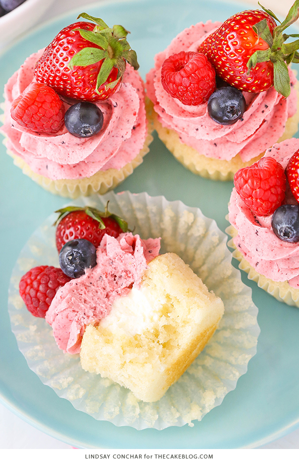 Berries and Cream Cupcakes - mixed berry buttercream paired with a moist vanilla cupcake stuffed with whipped cream cheese filling, topped with fresh strawberries, raspberries and blueberries | by Lindsay Conchar for TheCakeBlog.com
