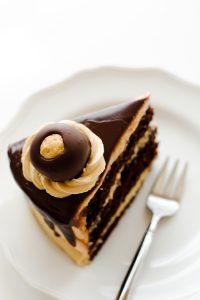 Chocolate Peanut Butter Cake - moist chocolate cake paired with peanut butter frosting and filling, topped with drippy chocolate ganache and homemade peanut butter balls, aka buckeyes | Carrie Sellman for TheCakeBlog.com