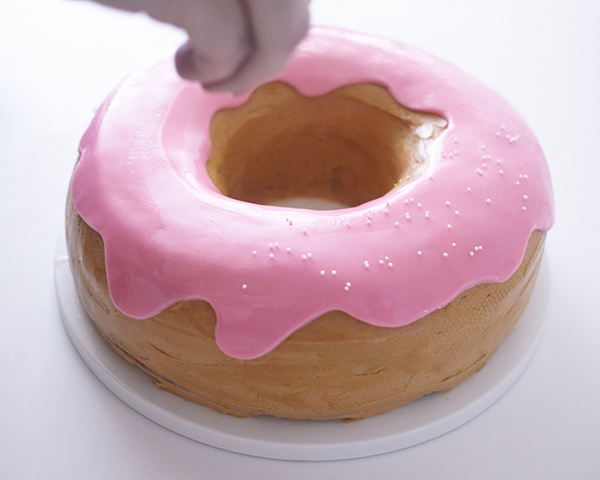 Giant Donut Cake! Learn how to make this adorable, sprinkle-coated, giant donut cake with a simple step-by-step tutorial | by Cakegirls for TheCakeBlog.com