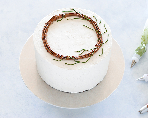 Spring Wreath Cake - how to make a buttercream wreath cake a bird's nest, cherry blossoms, green berries and cookie moss | by Carrie Sellman for TheCakeBlog.com #easter #easterdinnerideas #mothersday #cake