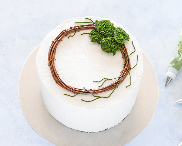 Spring Wreath Cake - how to make a buttercream wreath cake a bird's nest, cherry blossoms, green berries and cookie moss | by Carrie Sellman for TheCakeBlog.com #easter #easterdinnerideas #mothersday #cake