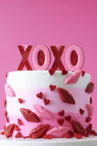 XOXO Valentine's Day Cake - how to make a pink ombre striped cake decorated with chocolate lips, hearts and an XOXO topper | by Cakegirls for TheCakeBlog.com